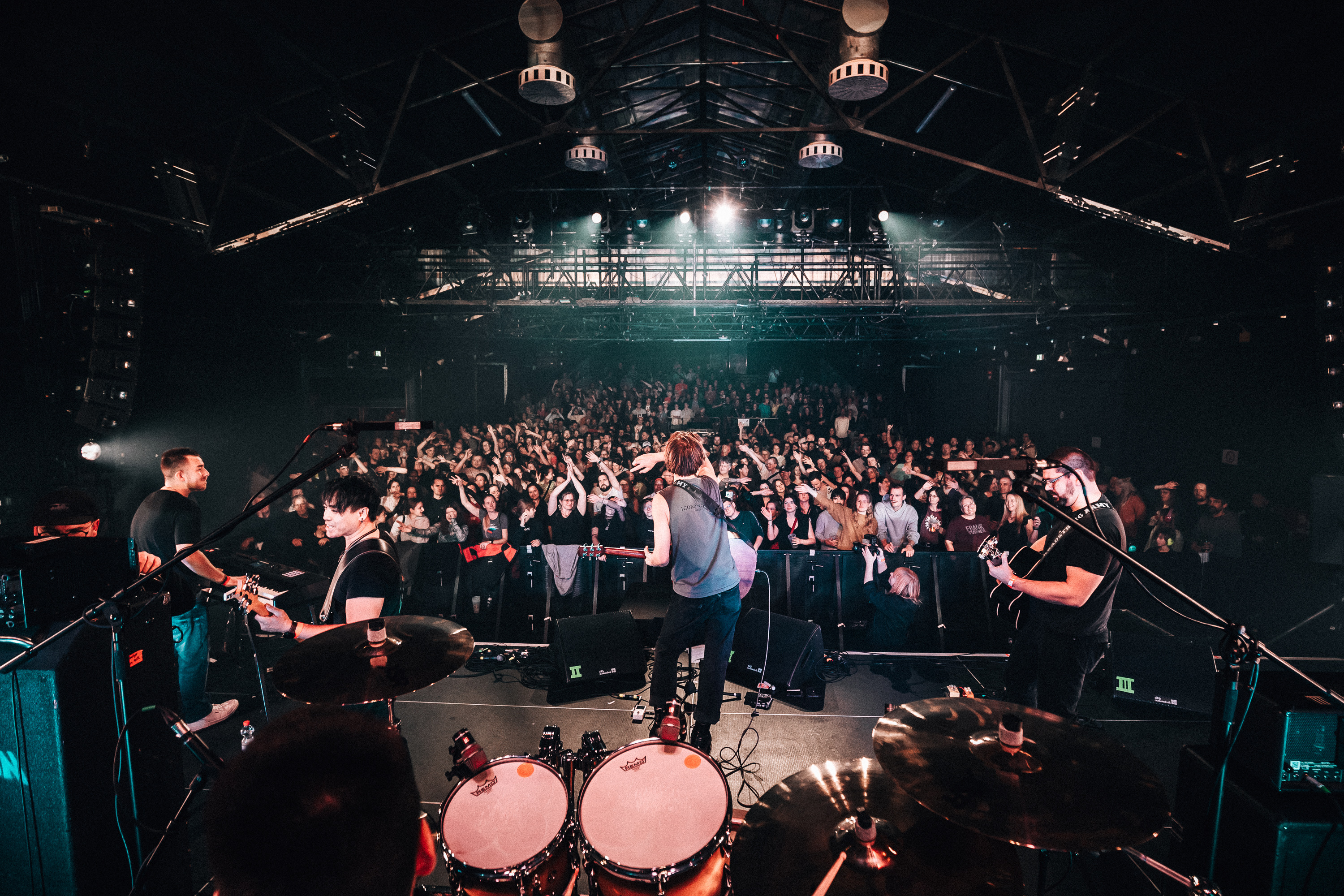 Blick von hinter dem Drumset auf Band und Publikum